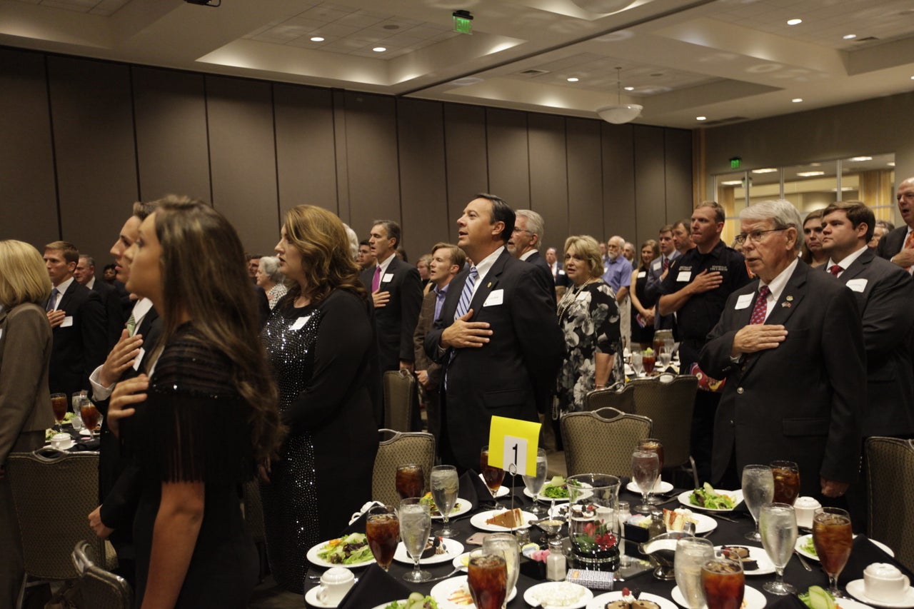 Attendees of Roy Moore's gala event hold their hands over their hearts for the Pledge of Allegiance.