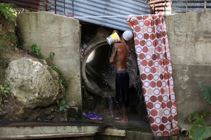 Israel Ayala takes a bath with water coming through a pipe on Oct. 19, 2017, after Puerto Rico was hit by Hurricane Maria in September.