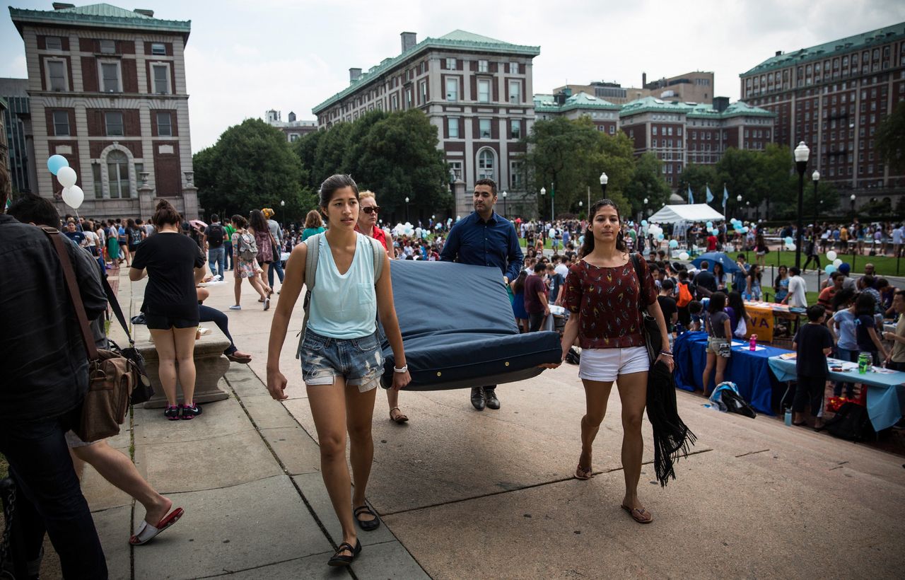 Emma Sulkowicz carries a mattress, with the help of three strangers who met her moments before, in protest of the university's lack of action after she reported being raped during her sophomore year at Columbia.