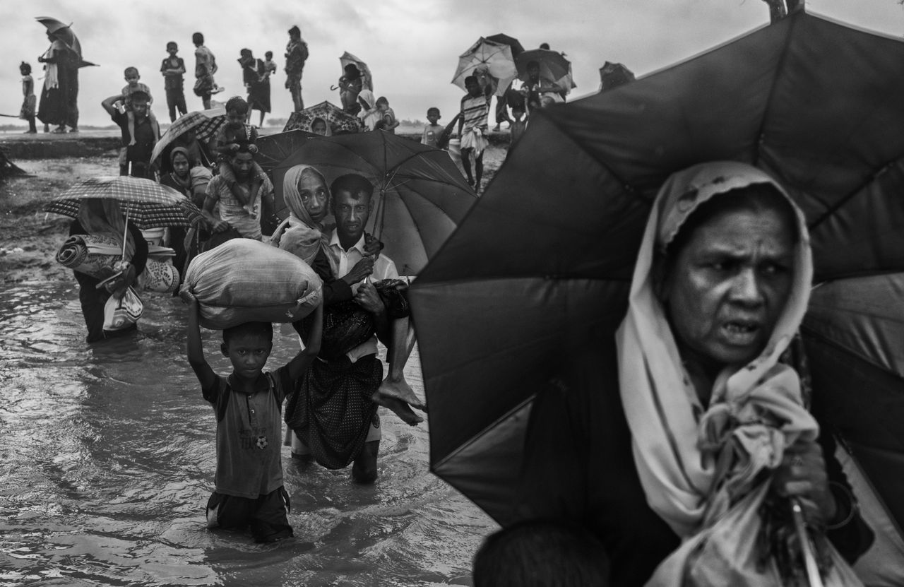 Rohingya refugees carry their belongings as they walk through water on the Bangladesh side of the Naf River after fleeing their village in Myanmar.