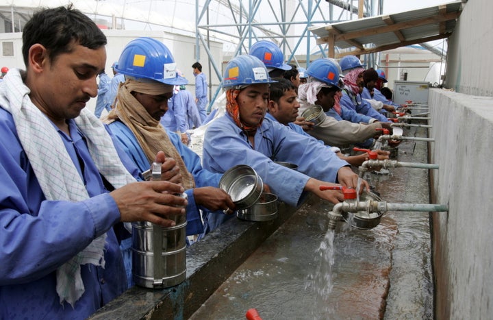 Workers of the Sport City tower wash their dishes after their lunch break in Doha, Qatar, Feb. 4, 2006.