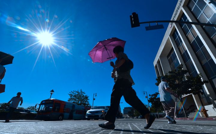 A pedestrian uses an umbrella as a heat shield in Los Angeles on Tuesday, when temperatures climbed past 100 downtown.