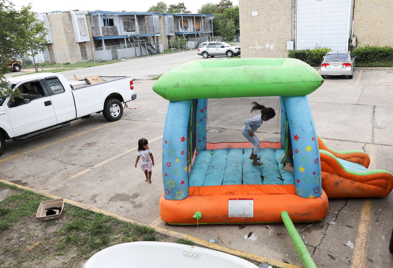 Monica Cruz, 7, jumps in an inflatable bouncy house as her neighbor Ashley Guerrero Monterrosa, 2, walks in the parking lot as residents clean up from Tropical Storm Harvey at Rockport Apartments.
