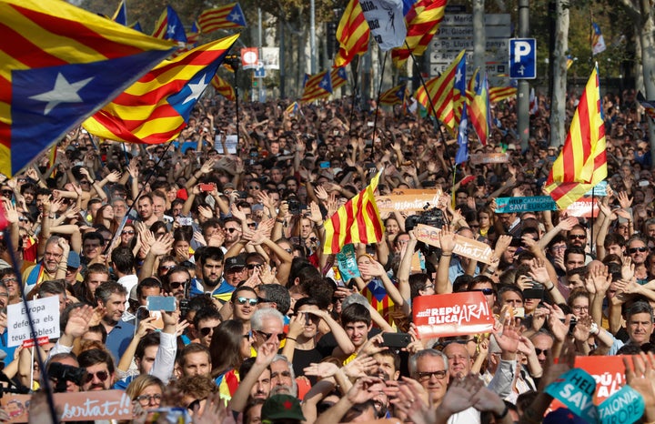 People react as they watch on giant screens a plenary session outside the Catalan regional parliament in Barcelona, Spain, Oc