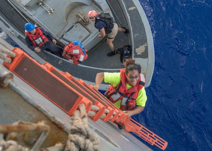 Tasha Fuiava, an American who had been sailing for five months on a damaged sailboat, climbs the ladder to board the amphibious dock landing ship USS Ashland.