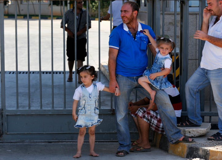 Syrian refugees wait at the Turkish Cilvegozu border gate, located opposite Syrian commercial crossing point Bab al-Hawa in Reyhanli, Hatay province, September 13, 2013.