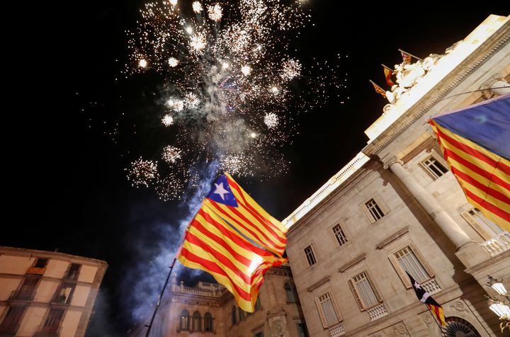 Catalan separatist flags are held up as fireworks go off in Sant Jaume Square in front of the Catalan regional government headquarters.