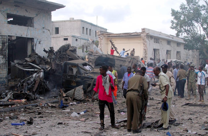 Somali security officers assess the damage at the scene of a suicide car bomb explosion, at the gate of Naso Hablod Two Hotel