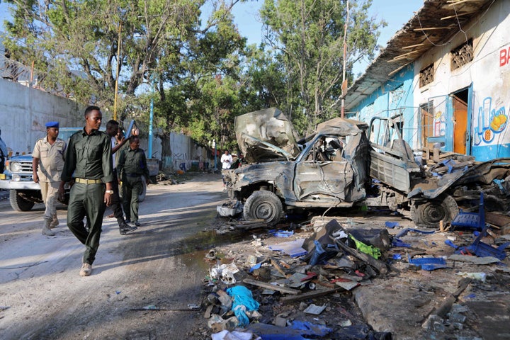 Somali security officers assess the scene of a suicide car bomb explosion, at the gate of Naso Hablod Two Hotel in Hamarweyne