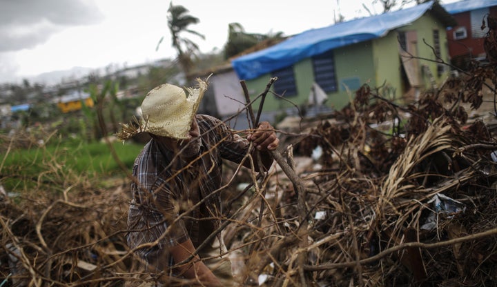 A man clears destroyed tree branches in a neighborhood in San Isidro, Puerto Rico, that's been without grid electricity for weeks. Eighty percent of the island hasn't had power for more than a month.