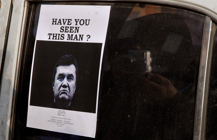 A man takes photos of a wanted notice of fugitive Ukrainian President Victor Yanukovich.