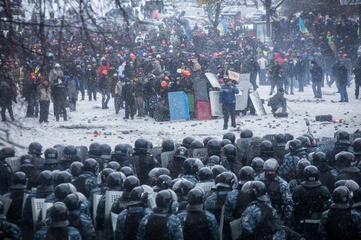 Riot police and Interior Ministry members stand in formation in front of pro-European protesters during clashes in Kiev on Jan. 22, 2014