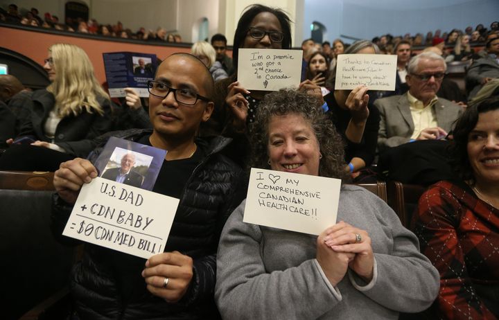 Members of the audience at Sanders' University of Toronto speech hold up cards with positive messages about Canadian health care.