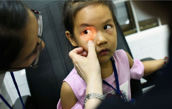 Child patient during eye exam with Orbis Volunteer Faculty members and local doctors in Binh Dinh, Vietnam.