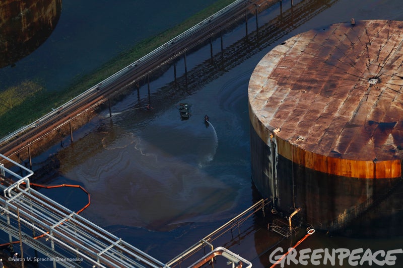 Workers in protective suits stand in the middle of oil covering Hurricane Harvey flood waters at the Petrobras Pasadena Refin