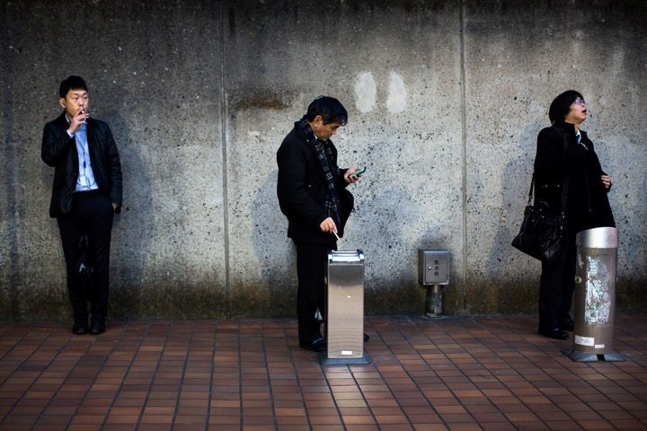 Men smoke cigarettes at a designated outdoor smoking area in the Naka-Meguro neighborhood of Tokyo. A local company is offering nonsmoking employees extra paid time off.