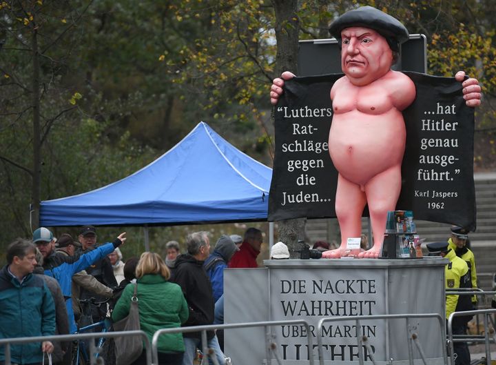 An effigy of German Church reformer Martin Luther reading 'The naked truth about Martin Luther' (on the socle) and 'Hitler precisely executed Luther's advices against the Jews' (in the coat) is seen close to the Schlosskirche (All Saints' Church, Castle Church) in Wittenberg, eastern Germany, where celebrations were under way on the occasion of the 500th anniversary of the Reformation on October 31, 2017. 