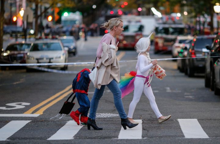 Kids in Halloween costumes cross the street near the scene where eight people were killed earlier in the day in a suspected terrorist attack in lower Manhattan.