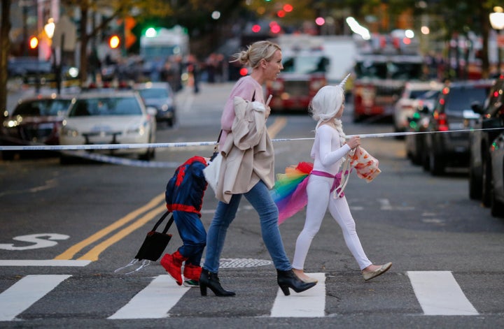 Kids in Halloween costumes cross the street near the scene where eight people were killed earlier in the day in a suspected t