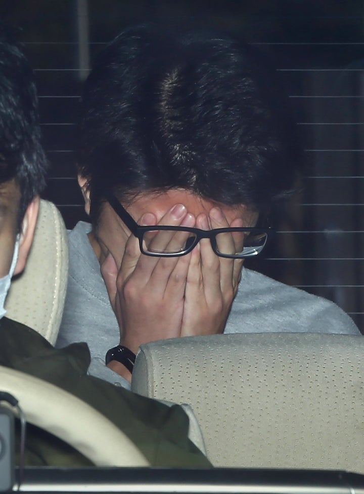 Suspect Takahiro Shiraishi covers his face with his hands as he is transported to the prosecutor's office from a police station in Tokyo on 1 November 