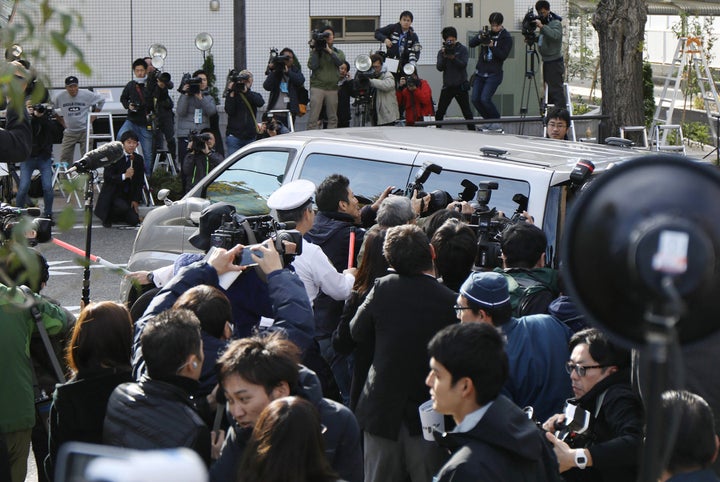 Photographers surround a police van transporting the suspect from a police station to the prosecutor's office in Tokyo 