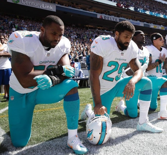 Miami Dolphin players “take a knee” during the pre-game National Anthem to protest discrimination and police violence against African Americans.