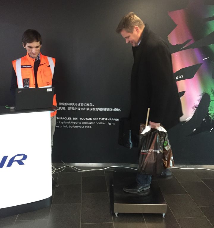 A Finnair pilot boards the scale with his carry-on bag at Helsinki Airport. He was one of some 180 volunteers to be weighed by the airline.