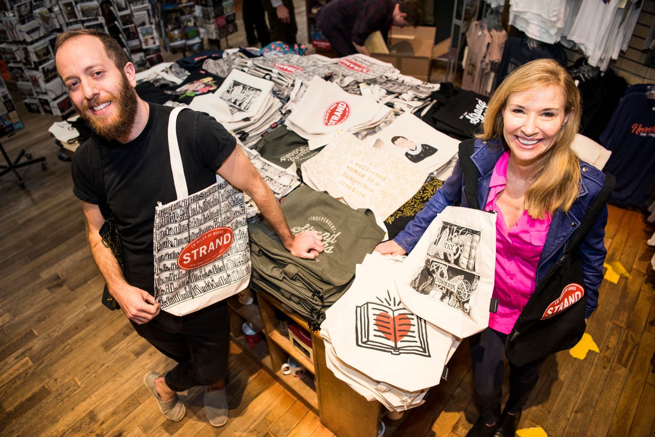 MacDonald and Strand co-owner Nancy Bass Wyden show off tote bags on sale at the Strand Bookstore in New York City.