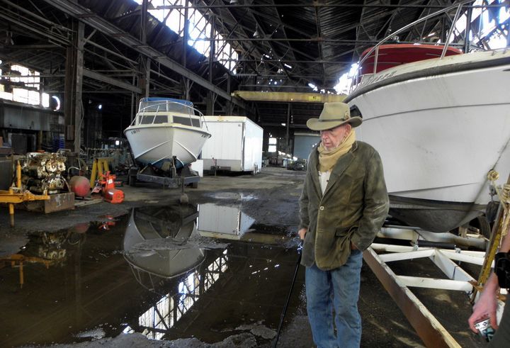 R.C. "Heck" Heckert inspects fire and water damage at one of his buildings adjacent to the site of the IEI fire. Heckert, who runs a taxi service and operates riverboats, says he lost three buildings to the fire, but doesn't blame IEI owners.