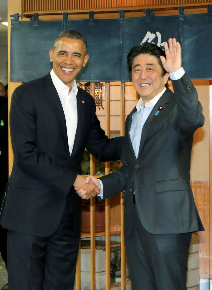 Obama and Abe shake hands in front of Sukiyabashi Jiro sushi restaurant.
