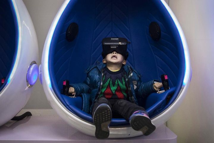 BEIJING, CHINA - NOVEMBER 26: A Chinese boy reacts while wearing virtual reality (VR) glasses in a roller coaster simulator at Leke VR Park, a leading chain. (Photo by Kevin Frayer/Getty Images)