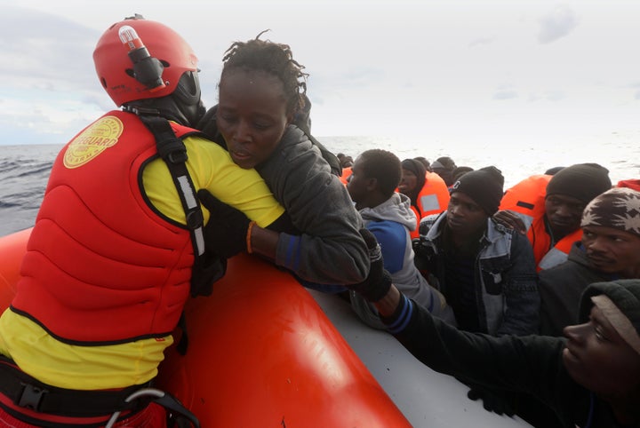 A lifeguard pulls a migrant woman to a rescue craft from an overcrowded raft in the central Mediterranean Sea, some 36 nautic