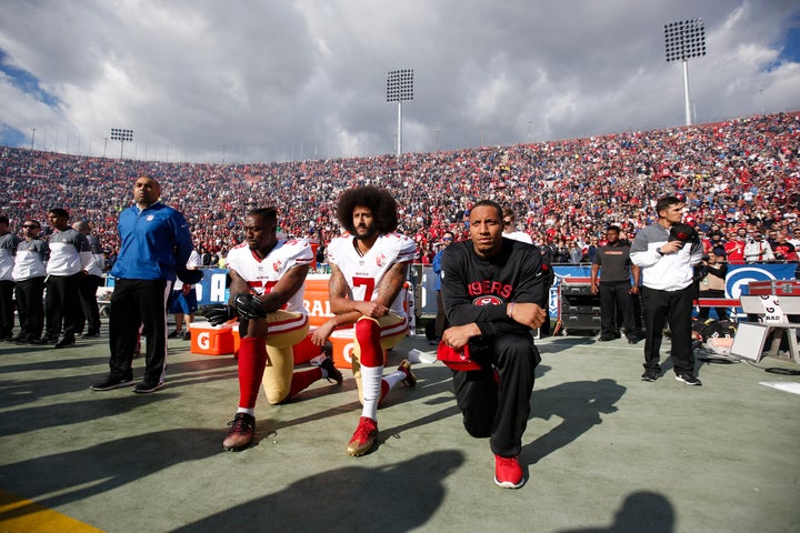 Eli Harold #58, Colin Kaepernick #7 and Eric Reid #35 of the San Francisco 49ers kneel on the sideline, during the anthem, pr