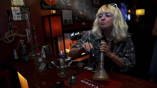 A Colorado woman smokes marijuana at a legal pot lounge in Colorado Springs. Lawmakers have legalized recreational marijuana and are debating whether to legalize such lounges.