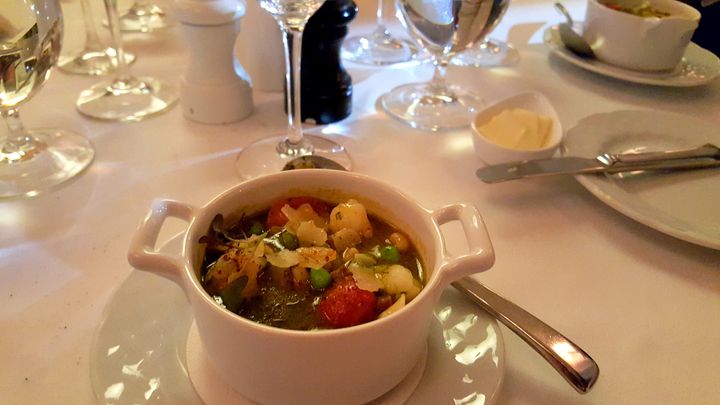 <p>Lemon Grass consomme with Gulf shrimp, local vegetables, tomatoes, served on a bed of crisp linens and polished silver.</p>