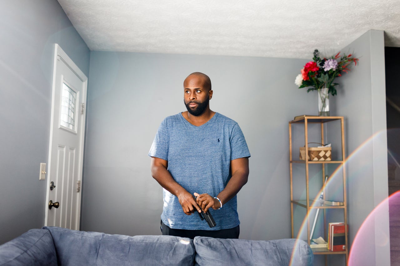 David White poses for a photo with his handgun in his home in Atlanta. He is a recent first-time gun owner.