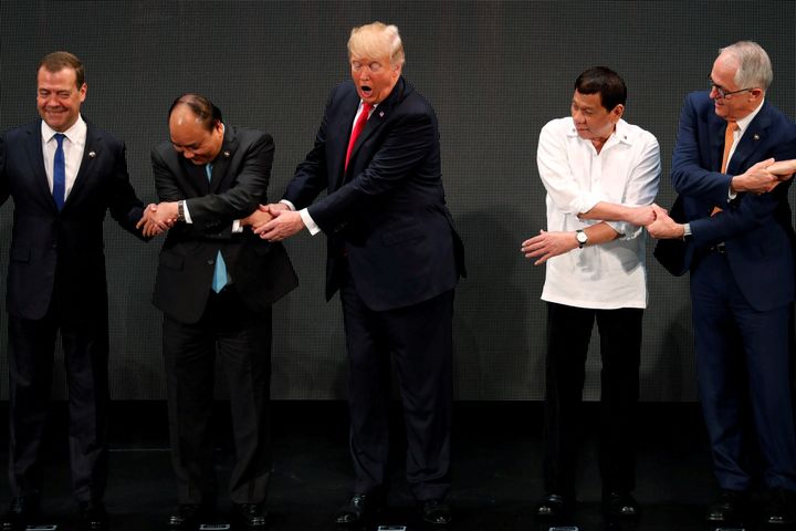 Trump breaks the line when he uses both hands to shake Vietnam Prime Minister Nguyen Xuan's hand, rather than crossing his arms to shakes hands with the leaders standing opposite him