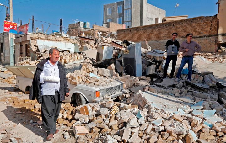 An injured Iranian walks through rubble in Sarpol-e Zahab, a town in Iran's western Kermanshah Province, on Tuesday.