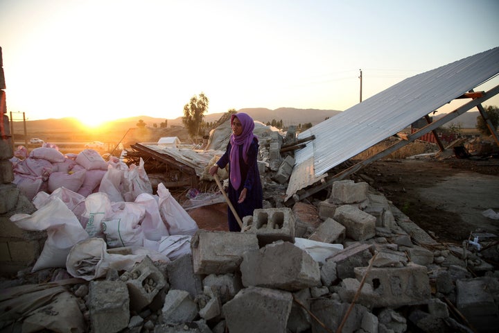 A woman struggles through the debris of a building in Kalaleh, Iran, on Tuesday, after a 7.3-magnitude earthquake Sunday.