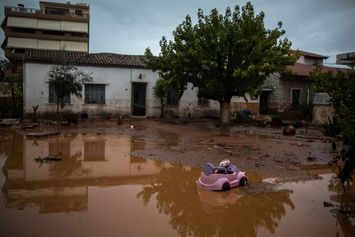 A toy car is seen in a flooded street next to a damaged house in the town of Mandra.