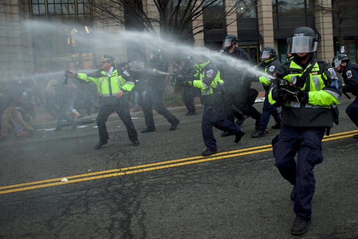 Police dispense pepper spray after a limousine was set on fire during the protests.