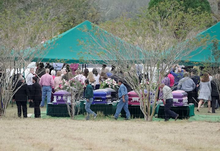 Mourners walk past caskets containing the bodies of members of the Holcombe and Hill families, victims of the Sutherland Springs Baptist church shooting, during a graveside service in Sutherland Springs, Texas, on Nov. 15