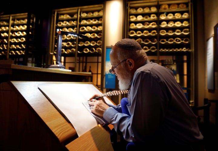 With ancient scrolls as a backdrop, Israeli Eliezer Adam works with ink and feather copying the Five Books of Moses, which he says will take a year, at the Museum of the Bible in Washington on Nov. 14.