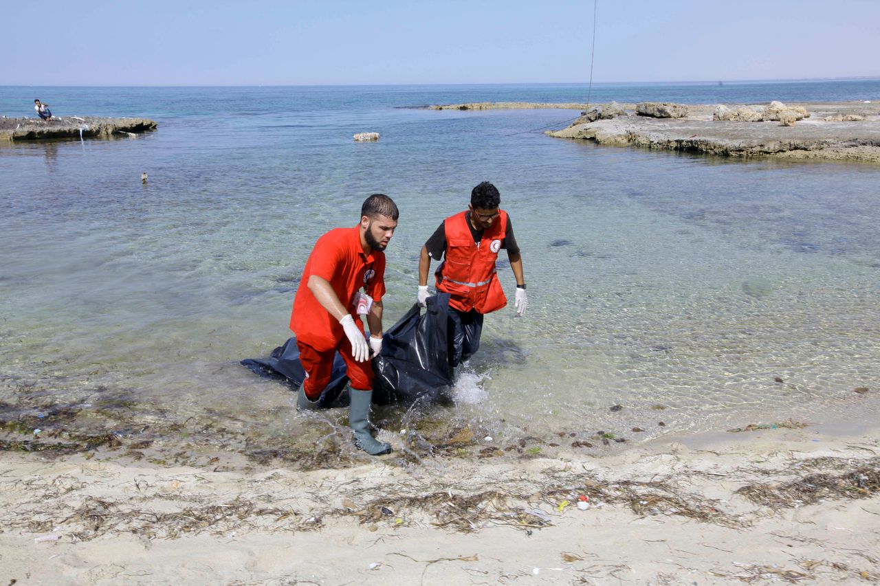 Rescuers carry a bag containing the body of a migrant at the coast of Tajoura, east of Tripoli, Libya, on June 27.