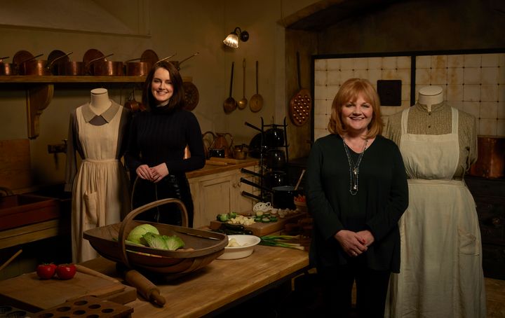 Sophie McShera (Daisy) and Lesley Nicol (Mrs. Patmore) pose with their costumes on the kitchen set at the exhibit.