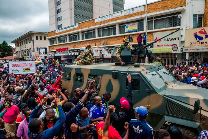 People cheer a passing Zimbabwe Defence Force military vehicle