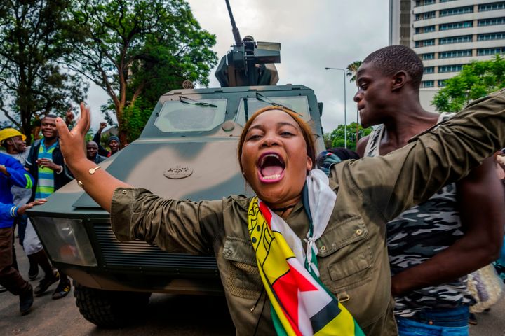 A woman reacts as people march with an armoured vehicle on the streets of Harare