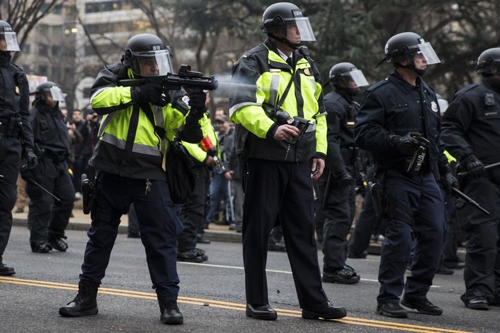 A police officer fires a beanbag round at anti-Trump protesters, Jan. 20, 2017.