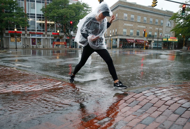 A woman jumps over a puddle after a heavy rain in Davis Square in Somerville, MA, in September