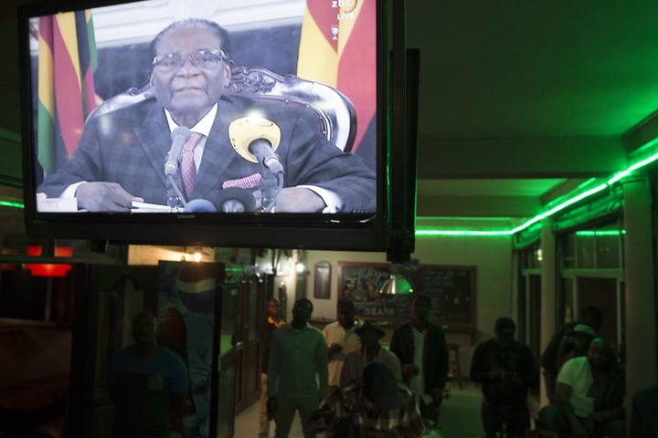 Zimbabweans watch a television broadcasting an address by President Robert Mugabe at Harare Sports Club in Harare on November